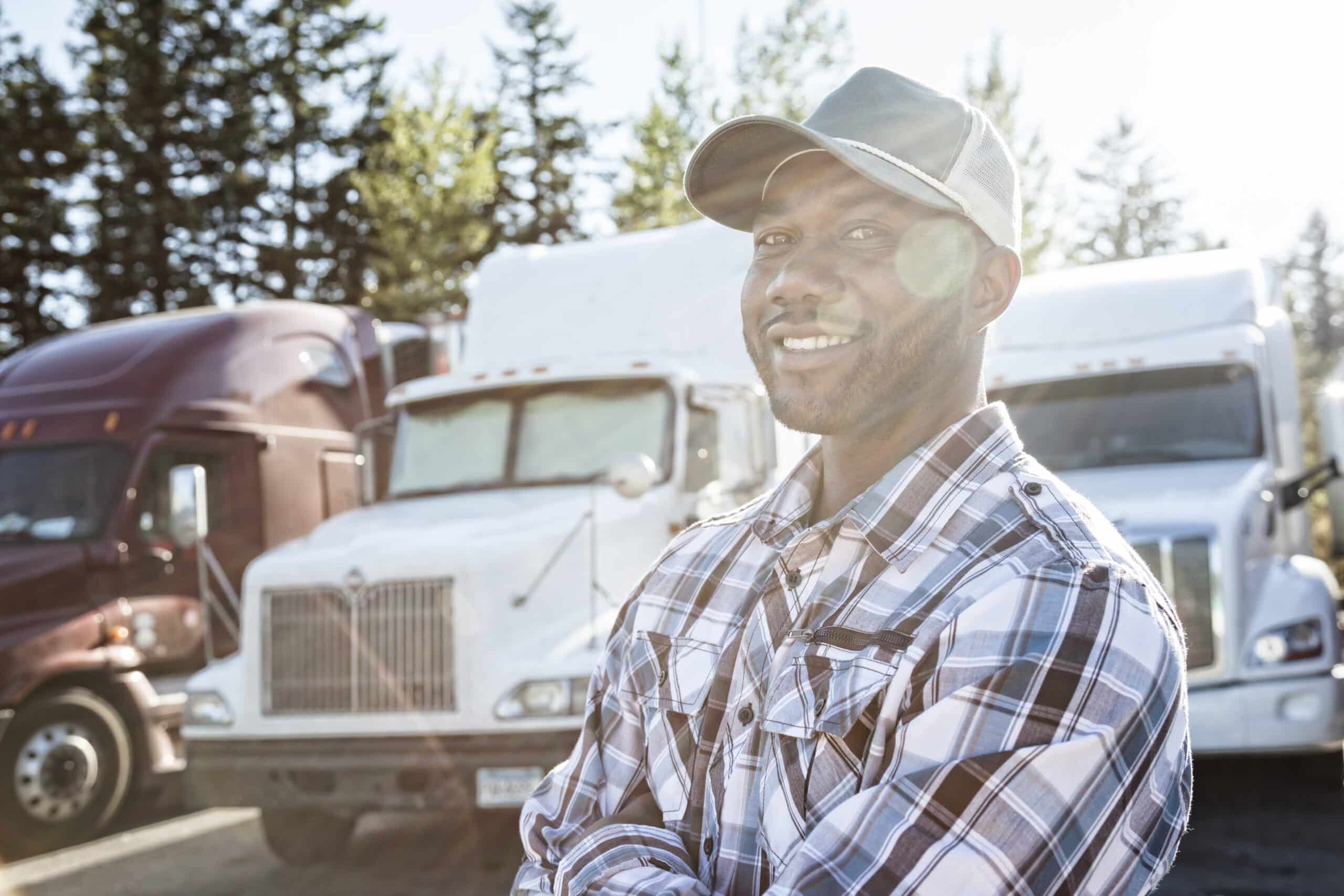 commercially insured Black man truck driver with commercial insurance near his truck parked in a parking lot at a truck stop